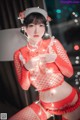 A woman in a red fishnet outfit holding a string of lights.