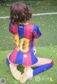 A little girl sitting on the ground with a soccer ball.