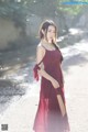 A woman in a red dress standing on a dirt road.