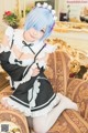 A woman in a maid outfit sitting on a couch.