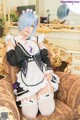 A woman in a maid outfit sitting on a couch.