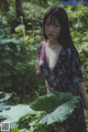 A woman standing in the middle of a lush green forest.