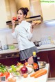 A woman in a kitchen holding a tomato and a potato.