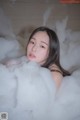 A woman laying in a bathtub filled with foam.