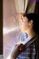 A woman in a kimono looking out of a window.