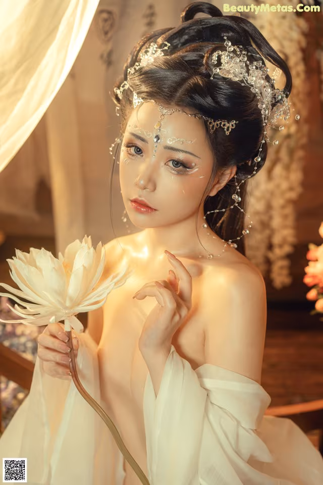 A woman in a white dress holding a white flower.