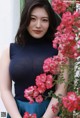 A woman standing in front of a bunch of pink flowers.