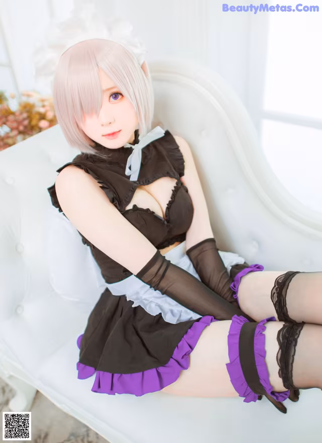 A woman in a maid outfit sitting on a white chair.