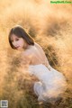 A woman in a white dress sitting in tall grass.